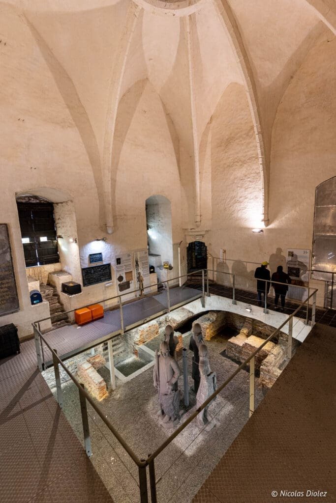 Intérieur du Beffroi de Gand : vestiges archéologiques et statues sous voûte.
