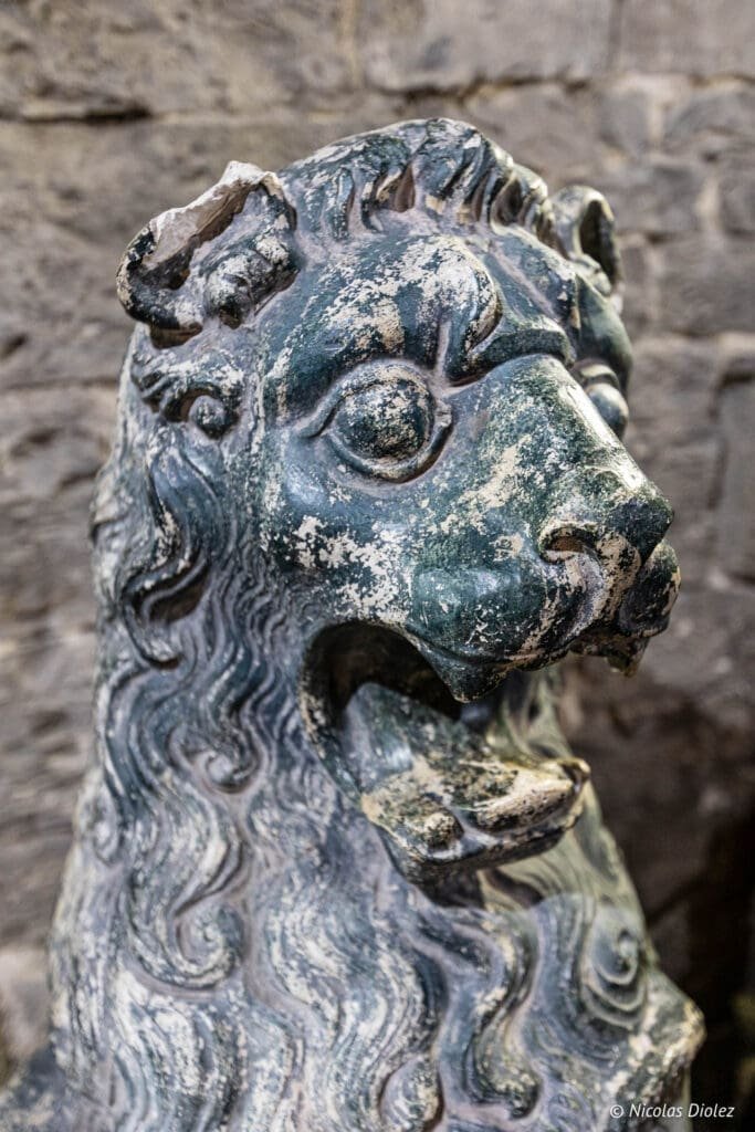 Statue de lion en pierre patinée, possiblement près du Beffroi de Gand.