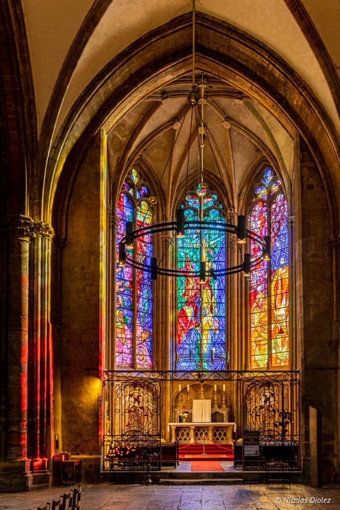 Intérieur Cathédrale Saint-Étienne de Metz: vitraux colorés, autel, et lustre suspendu.