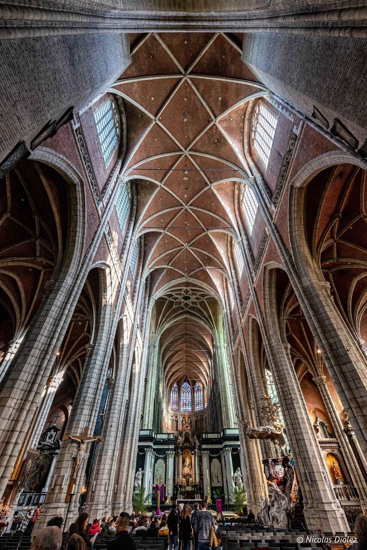 Intérieur cathédrale Saint-Bavon de Gand, voûte gothique et visiteurs.