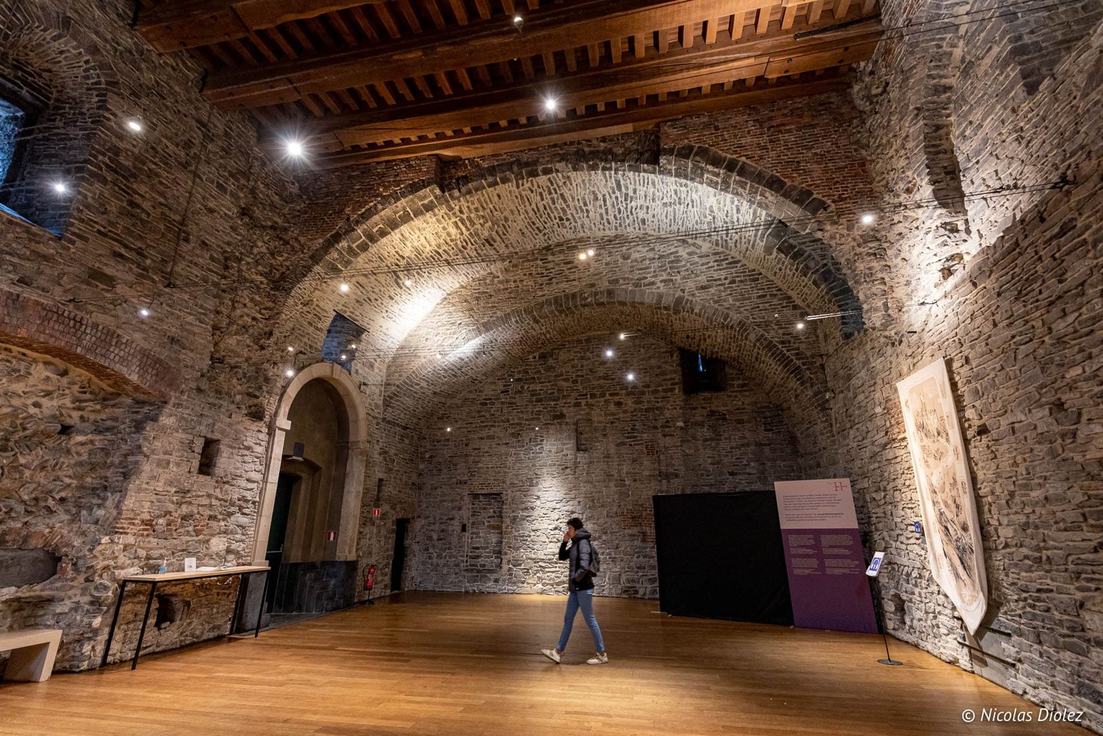 Intérieur voûté en pierre du Château des Comtes de Gand avec une visiteuse.