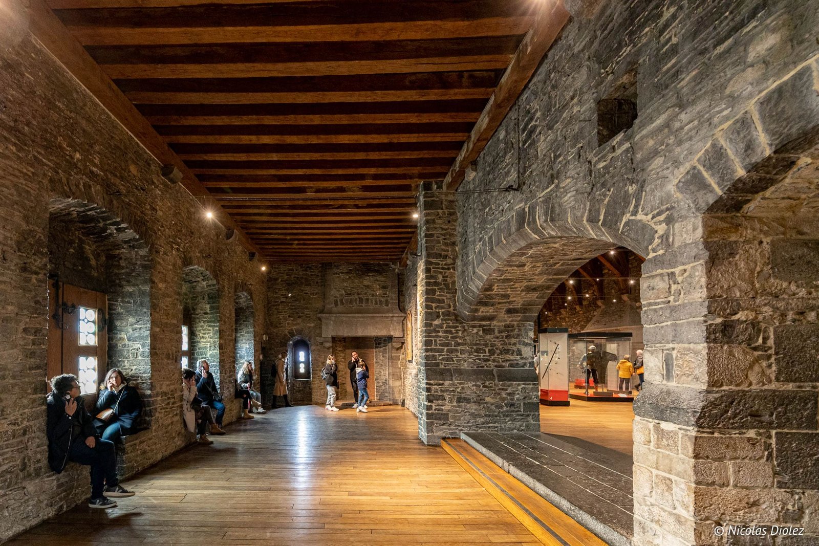 Intérieur médiéval du Château des Comtes de Gand avec poutres apparentes et visiteurs.