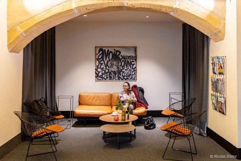 Intérieur d'hôtel MGallery La Citadelle Metz avec mobilier design et femme assise.