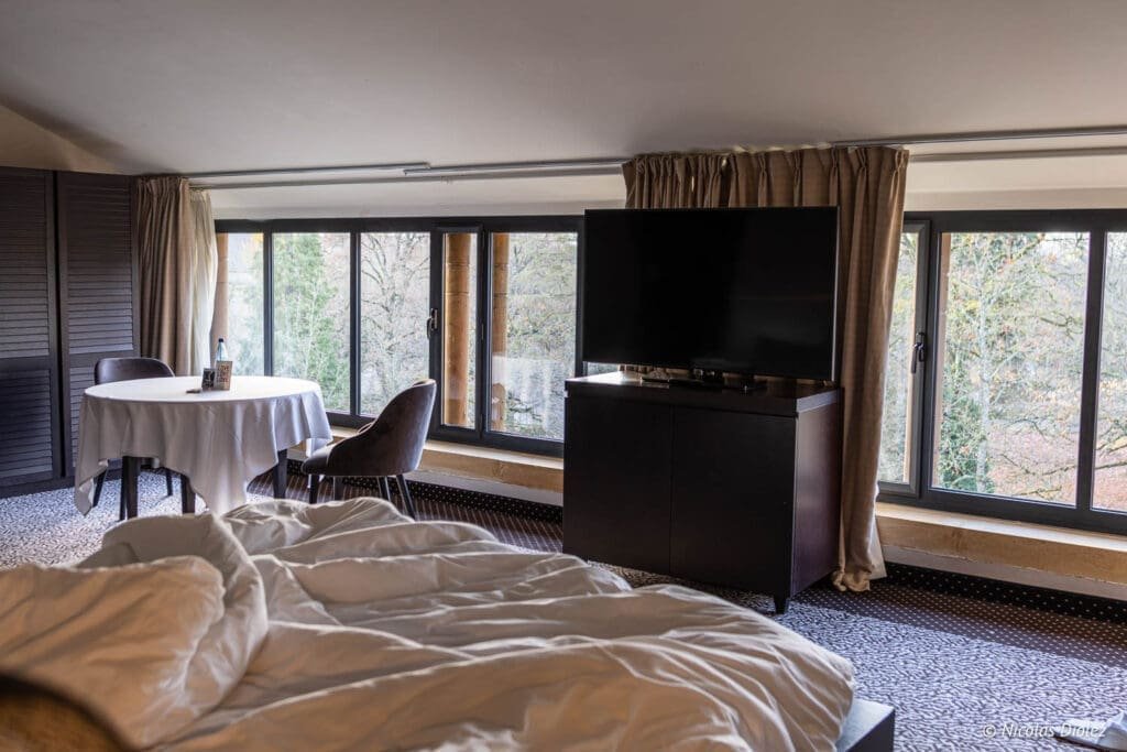 Chambre d'hôtel MGallery La Citadelle Metz avec lit défait et vue sur l'extérieur.