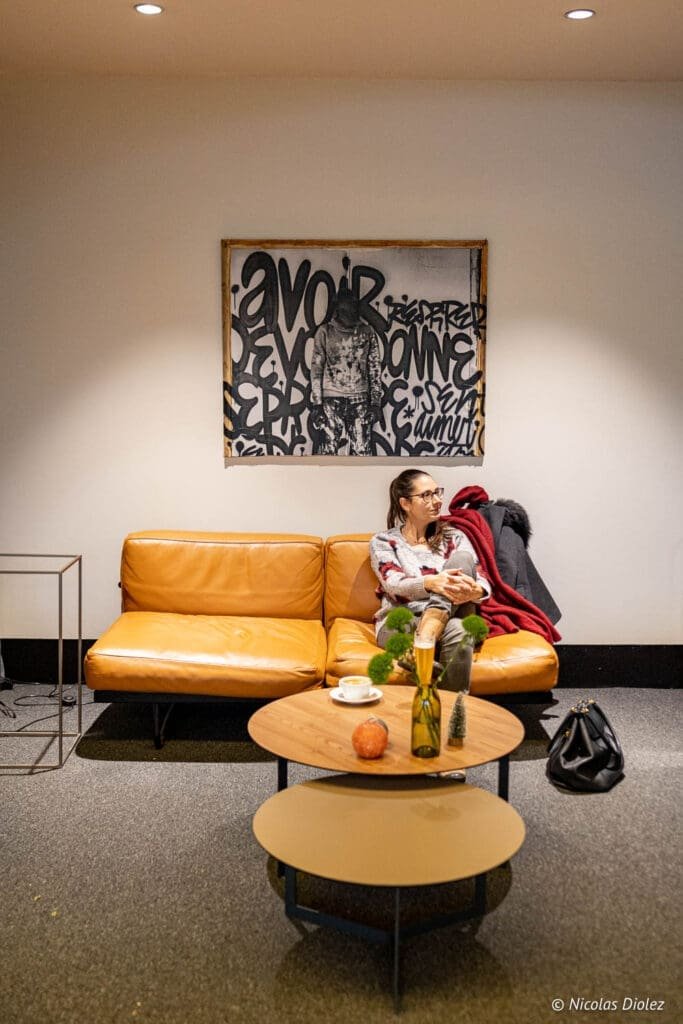 Lobby avec une femme sur canapé en cuir, Hôtel MGallery La Citadelle Metz.