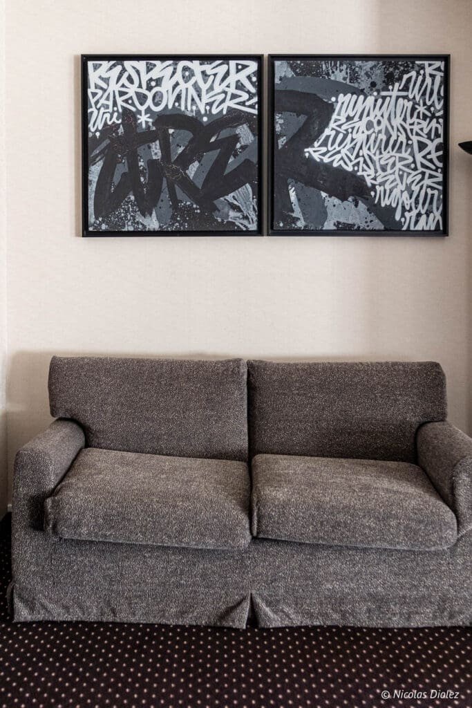 Canapé gris et tableaux de style graffiti à l'Hôtel MGallery La Citadelle Metz.