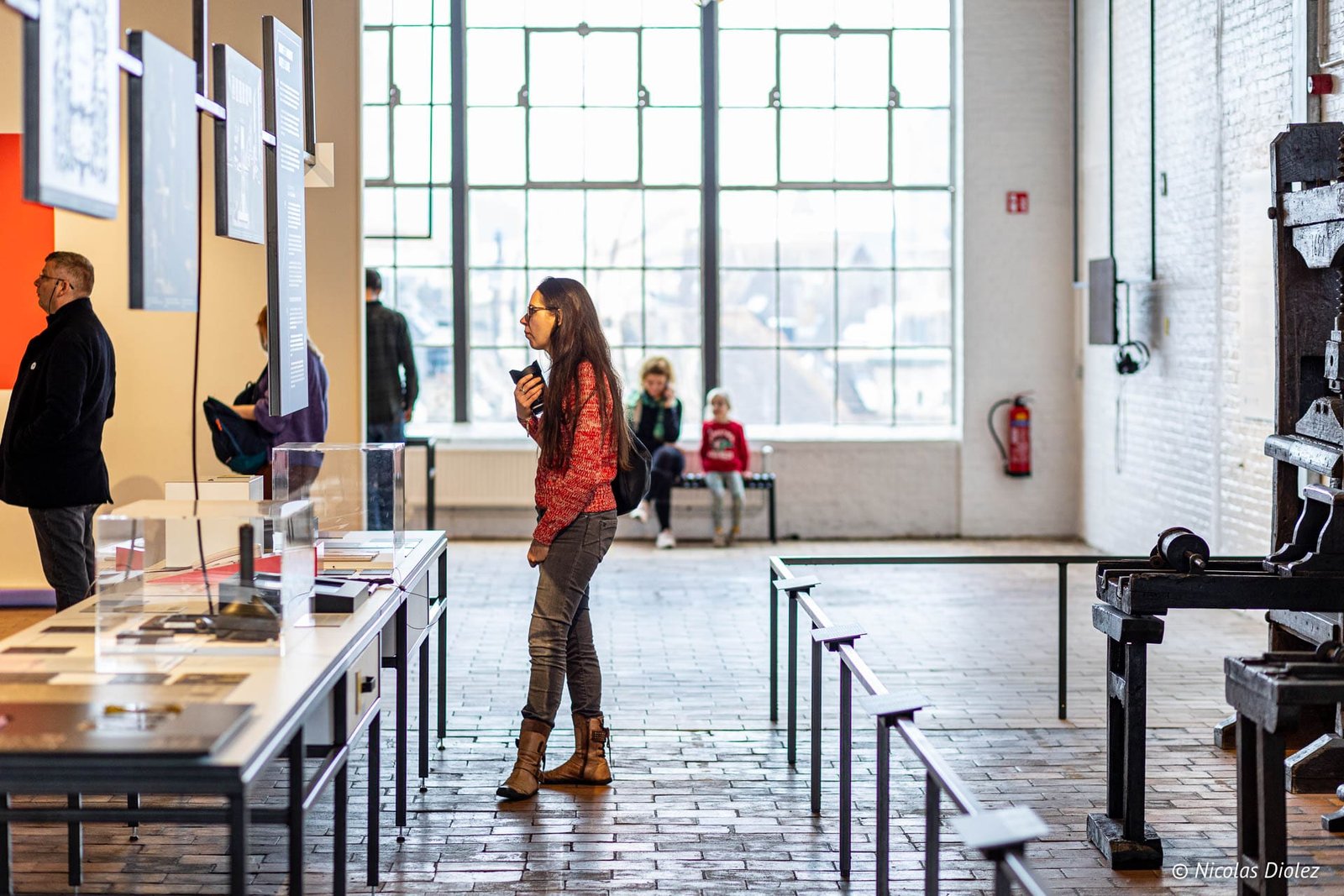 Visiteurs dans le Musée de l'Industrie de Gand devant des expositions et machines anciennes.