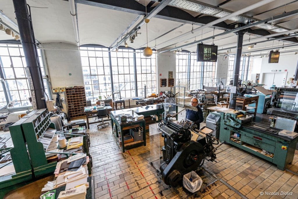 Intérieur du Musée de l'Industrie de Gand avec presses d'imprimerie et technicien.