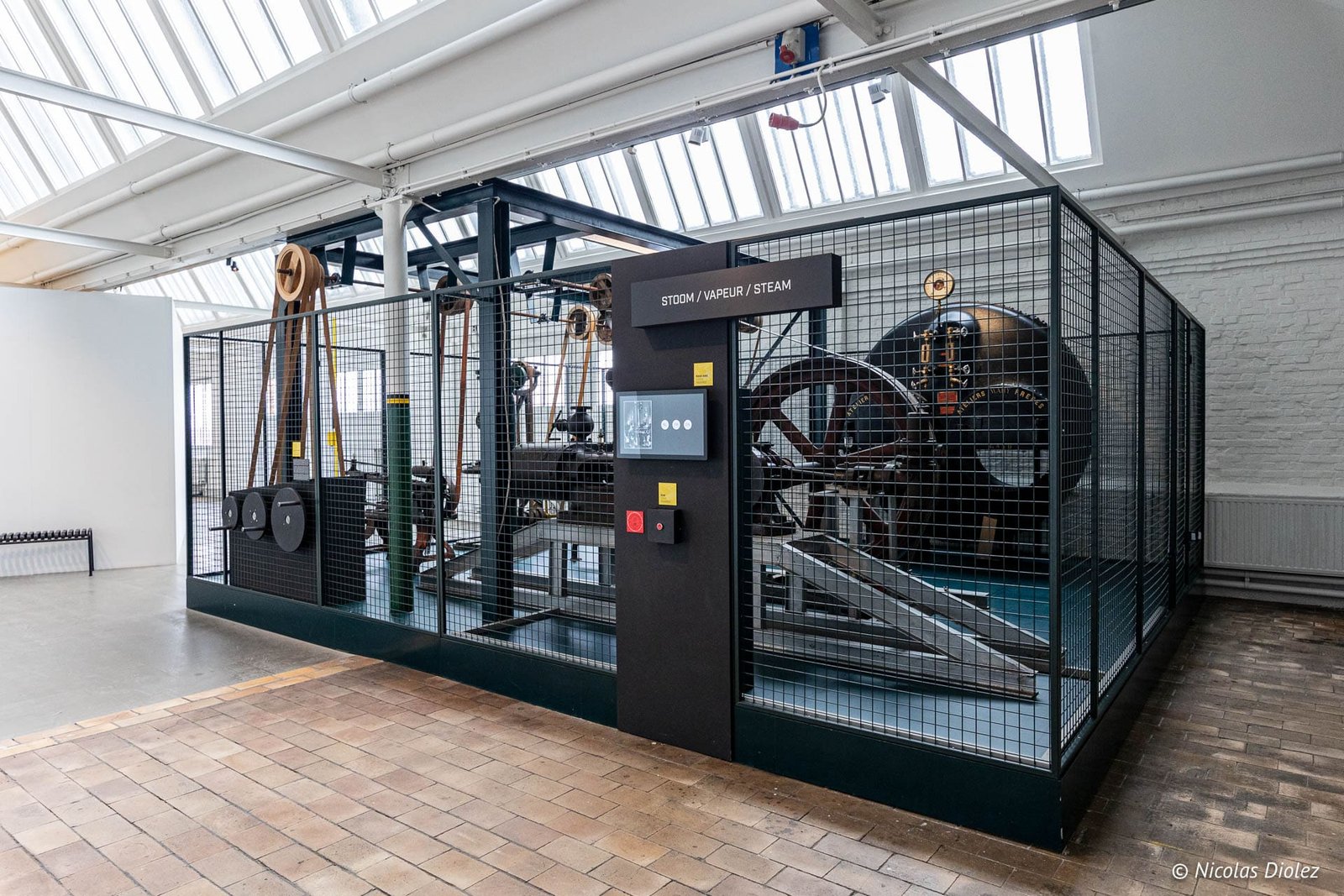 Machine à vapeur historique derrière une grille au Musée de l'Industrie de Gand.