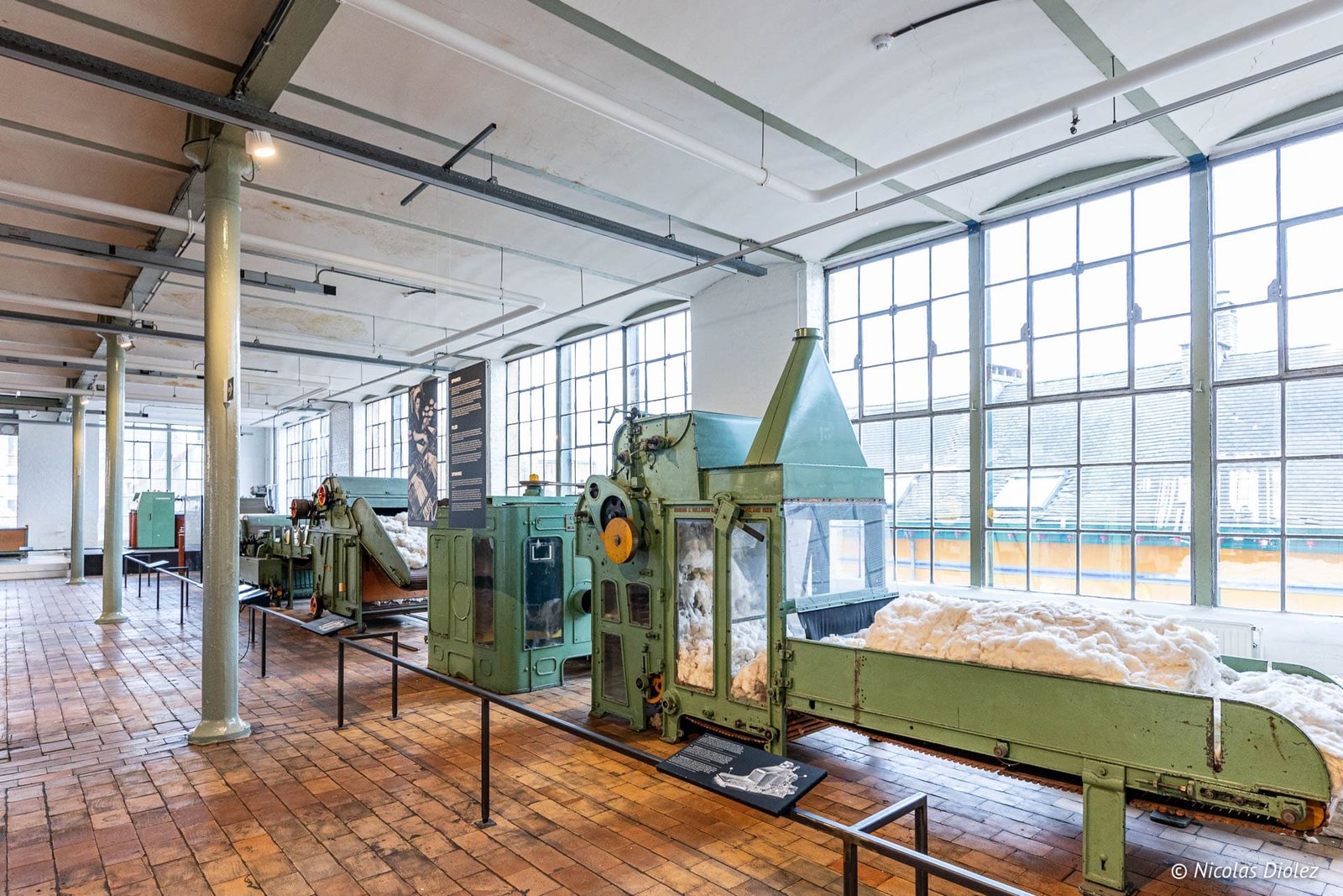 Machine textile industrielle verte avec coton brut exposée au Musée de l'Industrie de Gand.