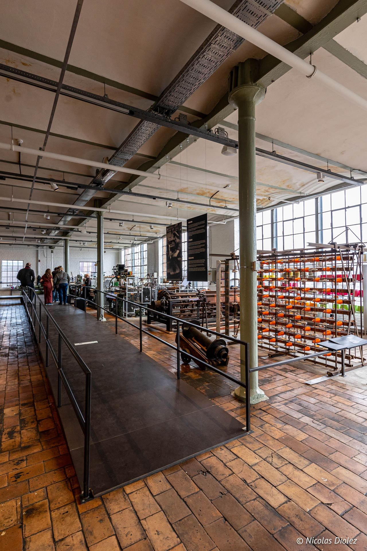 Intérieur du Musée de l'Industrie de Gand avec machines textiles et visiteurs.