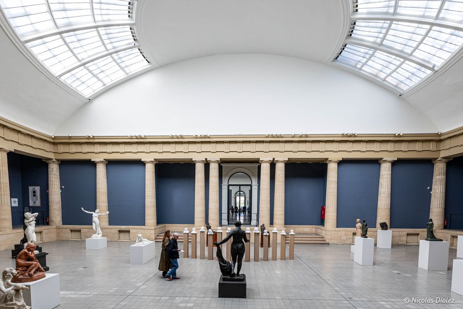 Intérieur du Musée des Beaux-Arts de Gand avec sculptures et visiteurs sous verrière.