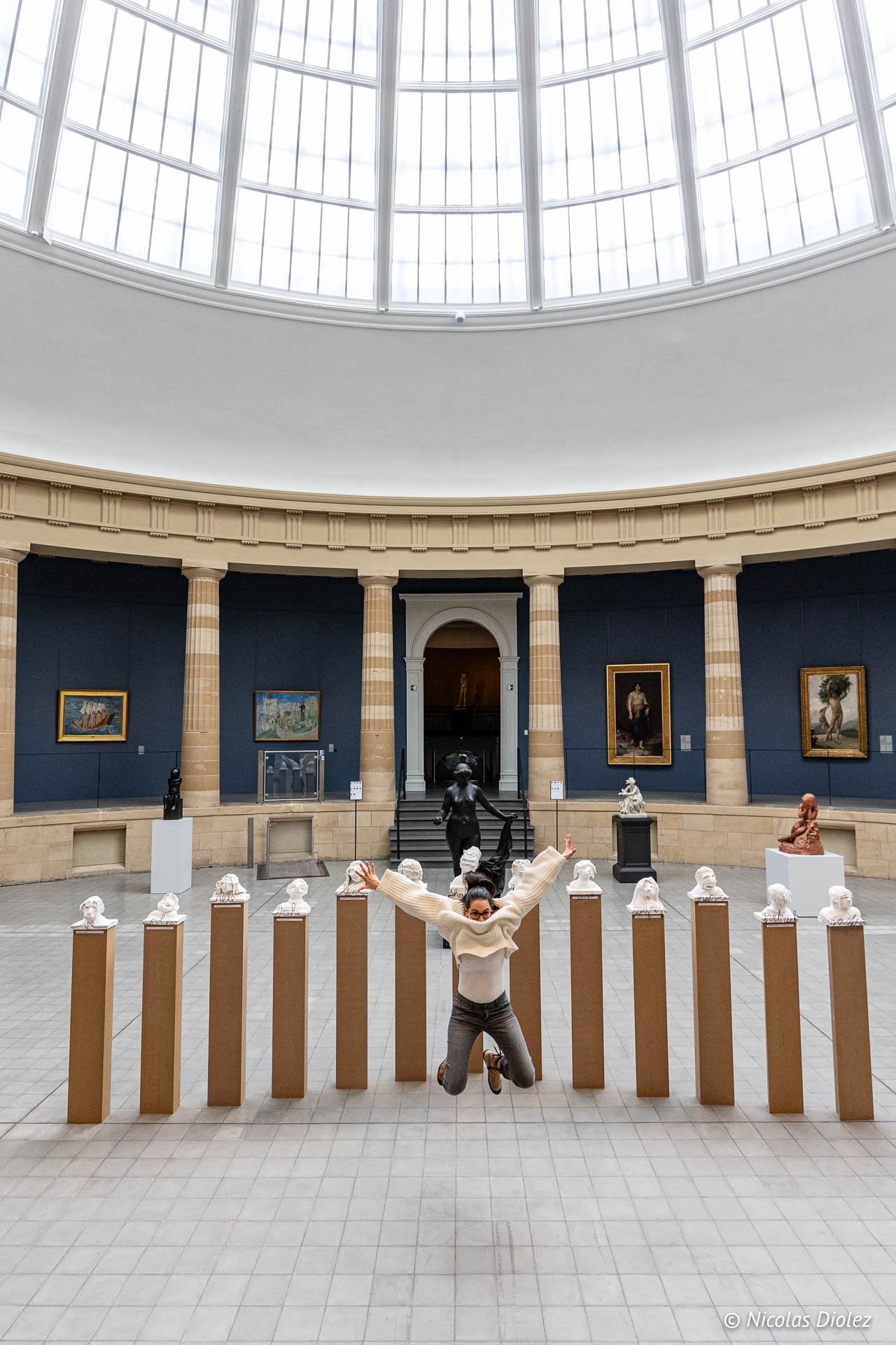 Joueuse sautant entre des bustes au Museum voor Schone Kunsten Gent.