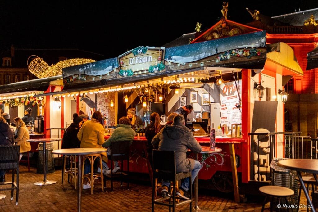 Chalet du marché de Noël de Metz "O'Flamm" la nuit avec des clients.