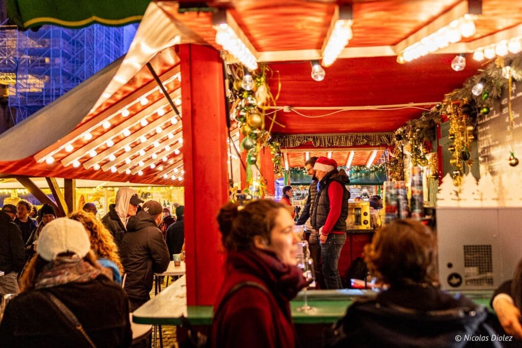 Client du marché de Noël de Metz sous un chalet décoré de lumières et de décorations.