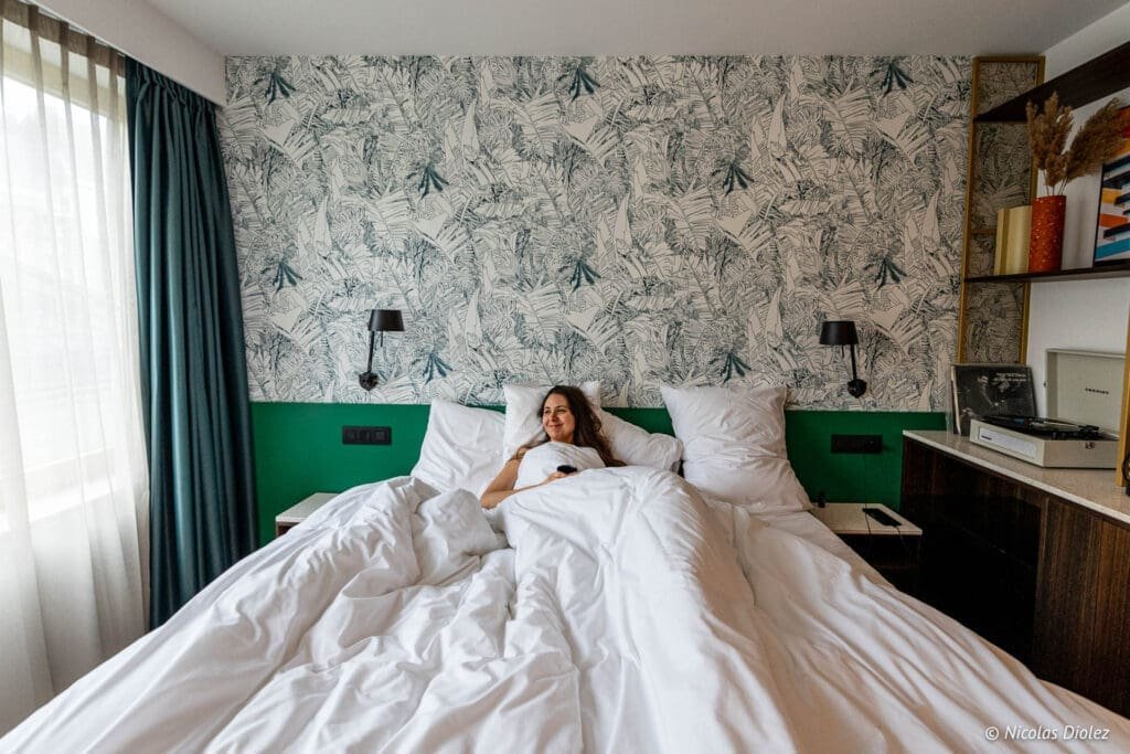 Smiling woman in a cozy bed at Yalo Hotel Ghent.