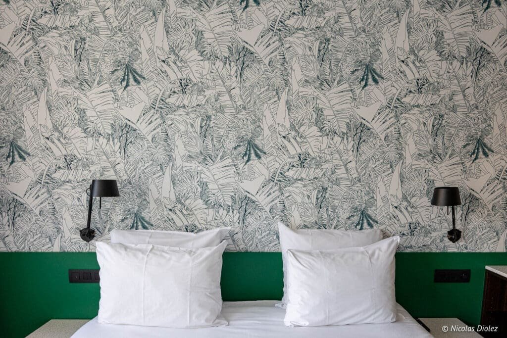 Chambre Yalo hôtel Gand avec tête de lit verte et papier peint jungle.