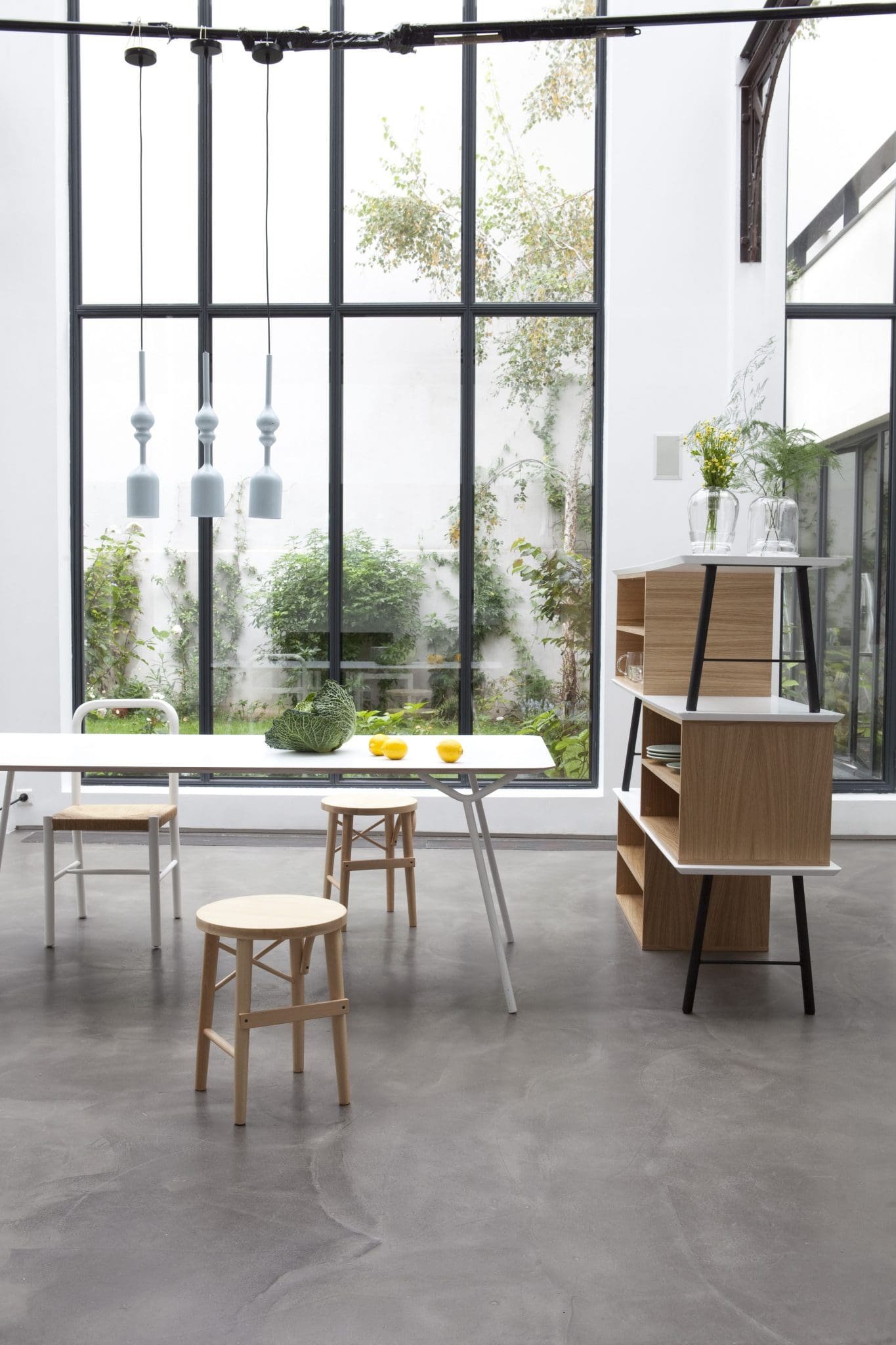Salle à manger moderne avec grands luminaires suspendus et vue sur jardin.