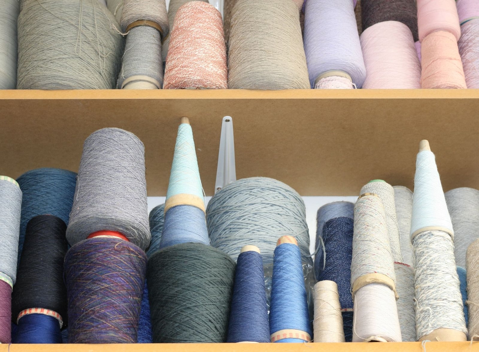 Bobines de fil coloré sur des étagères de magasin de tissus ou d'artisanat.