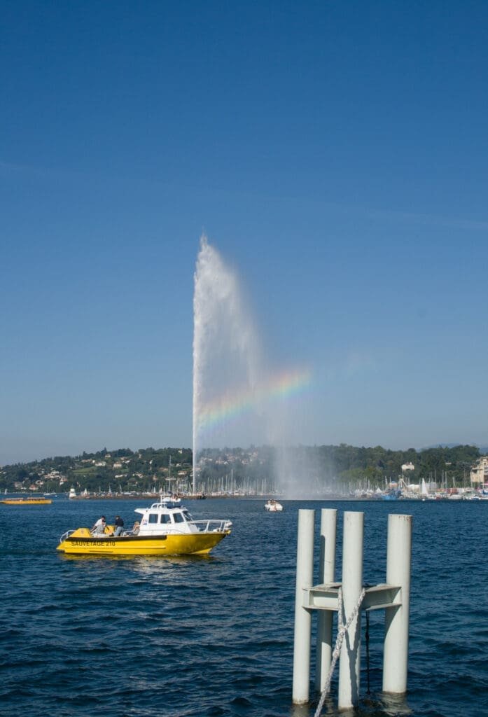 Jet d'Eau Genève avec arc-en-ciel et bateau Sauvetage 210 sur le lac.