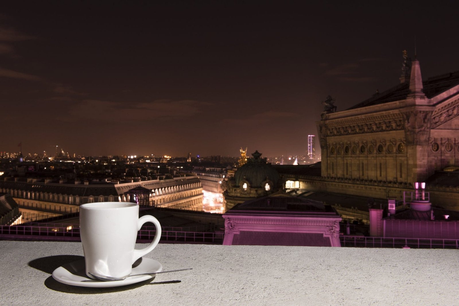 Tasse blanche sur terrasse vue nocturne Paris, toits et Opéra Garnier.