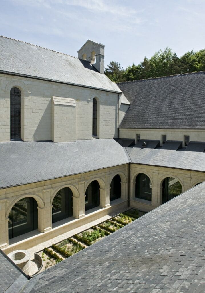 Cloître de l'Abbaye Royale de Fontevraud avec toiture en ardoise et jardin.