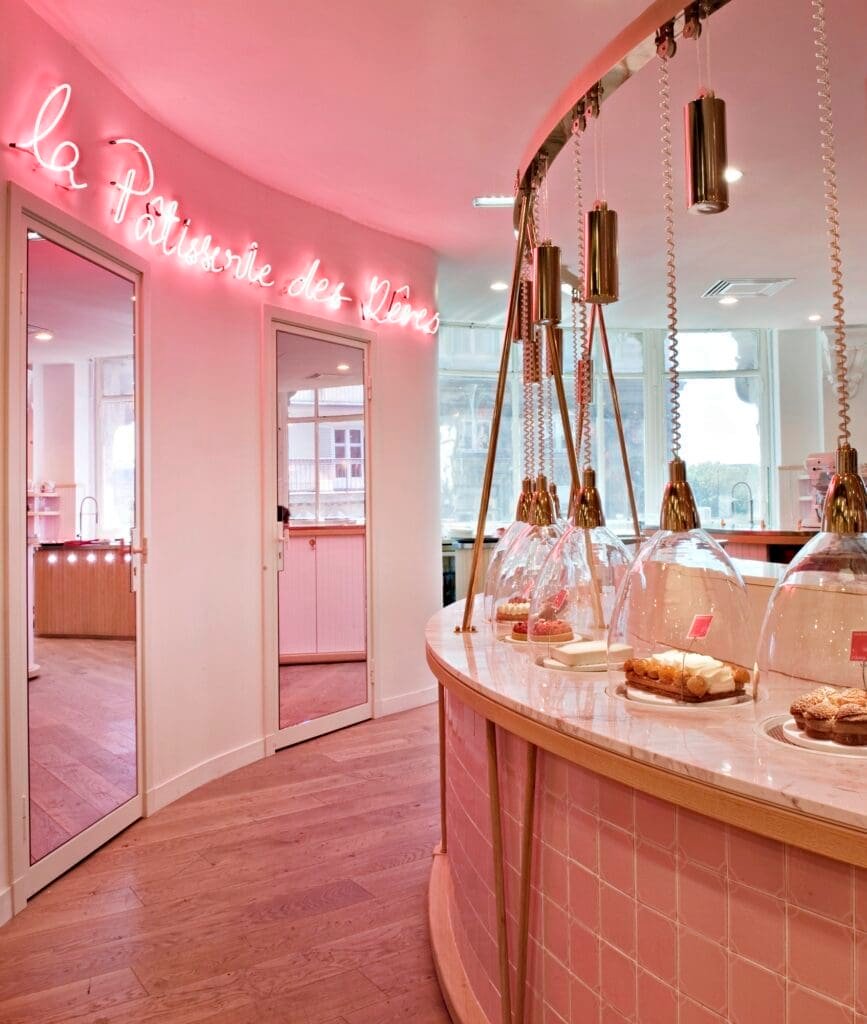 Interior rosa neón Pâtisserie des Rêves con mostrador y vitrinas.