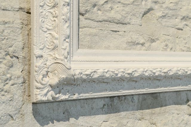 Cadre blanc sculpté sur mur de pierre, exposition Val d'Oise.