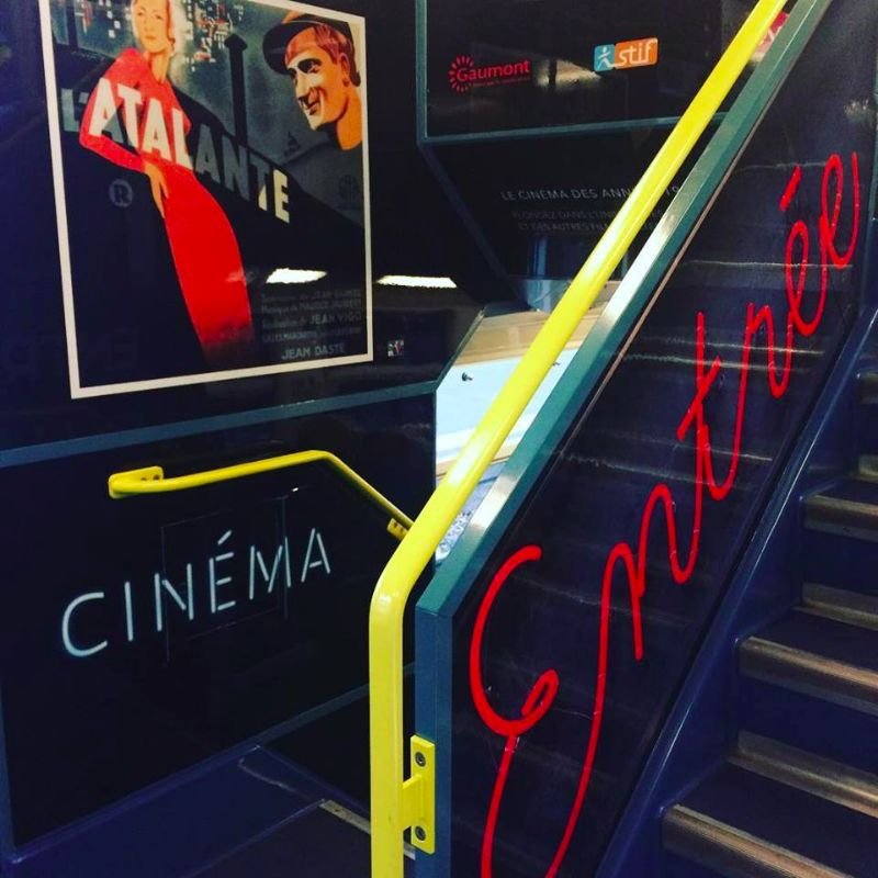 cinéma Escalier avec signalétique CINÉMA, affiche L'Atalante et néon Entrée.