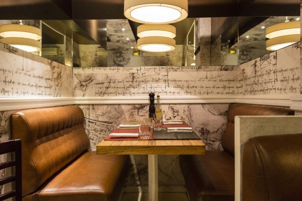 Banquettes en cuir marron et table dressée dans une pizzeria parisienne.
