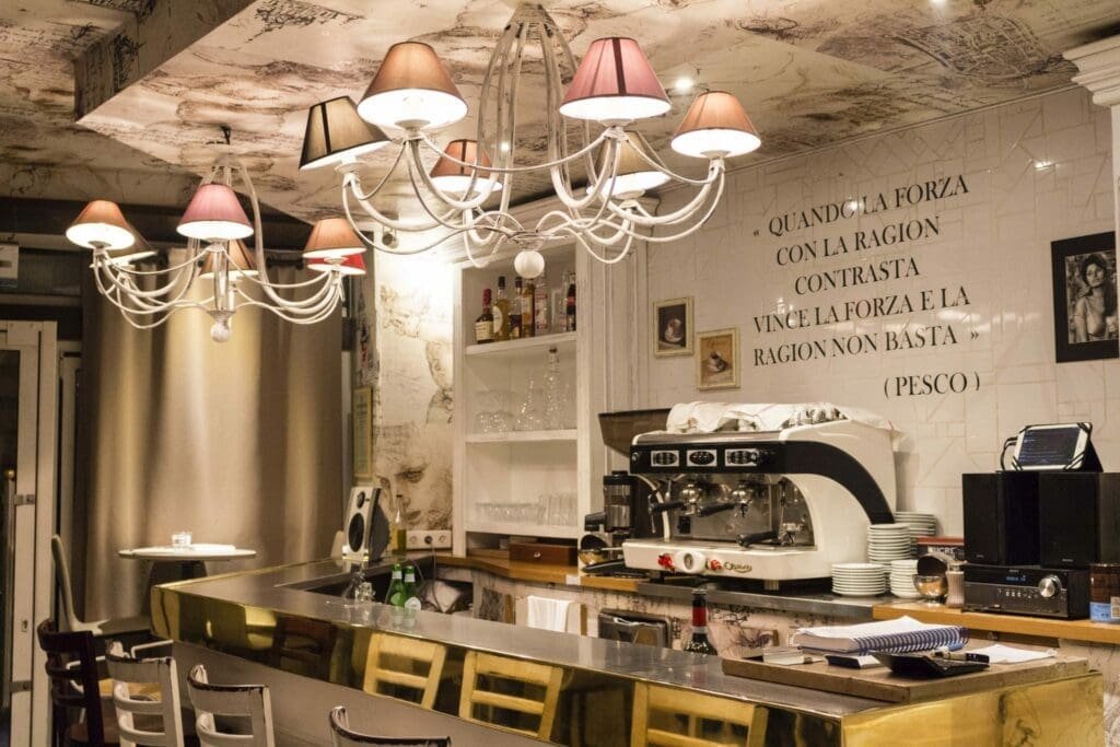 Intérieur de bar italien avec machine à café et citations sur mur carrelé.