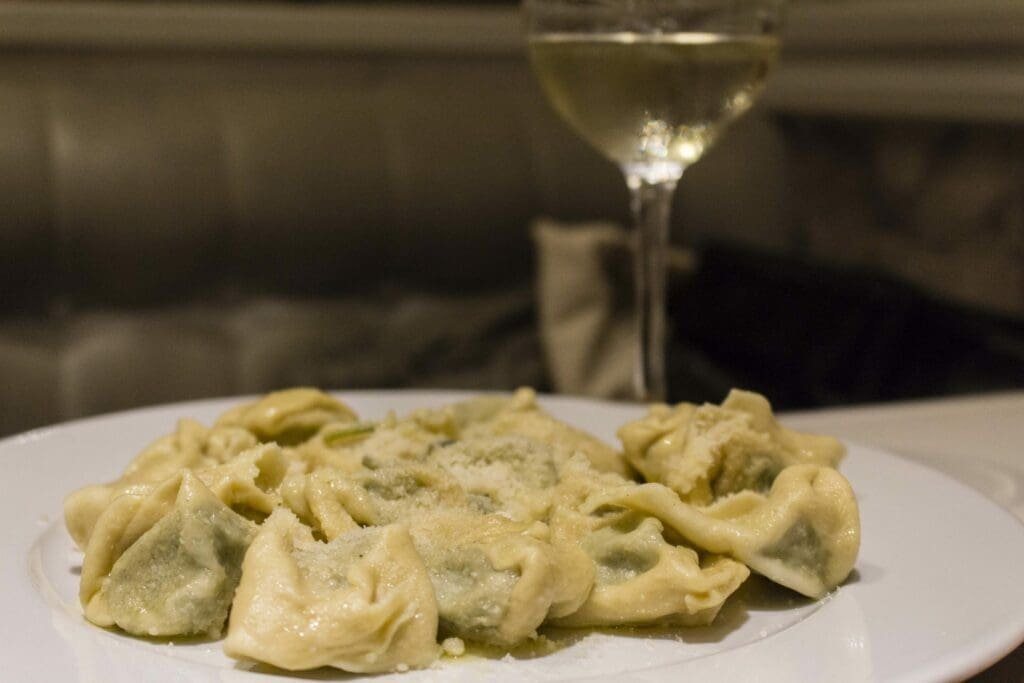Pâtes farcies au parmesan et verre de vin blanc sur assiette.