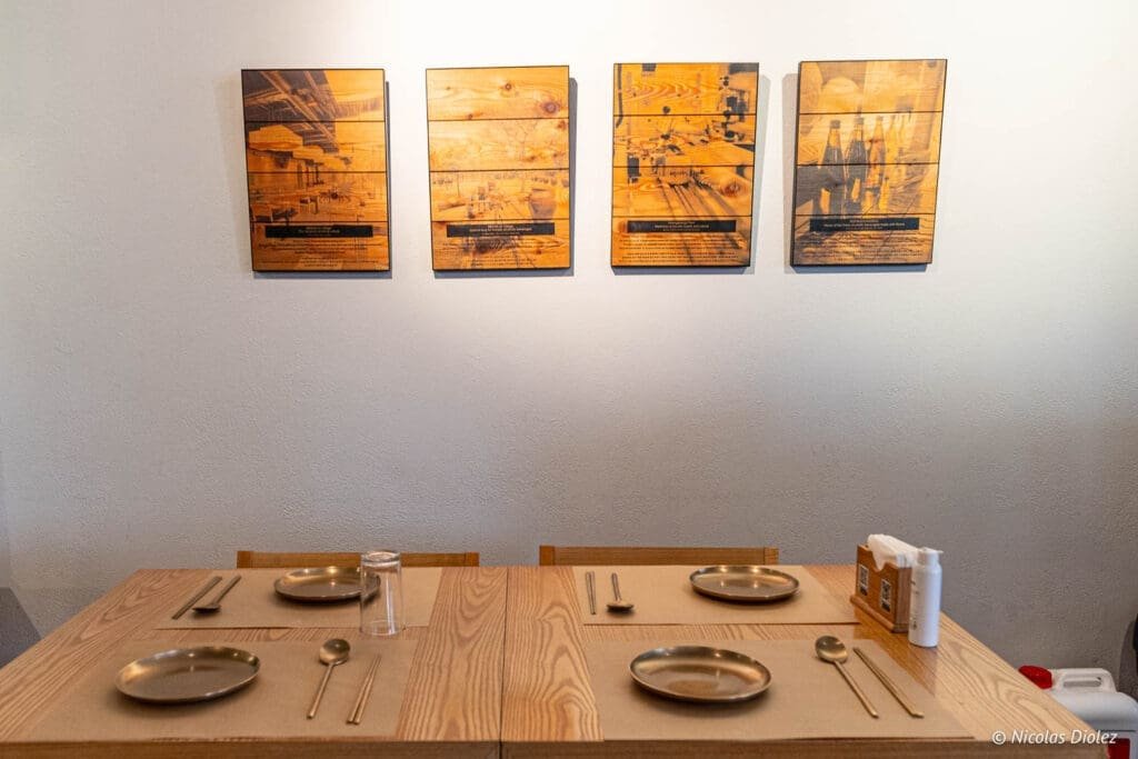 Table dressée au restaurant Bekseju Village avec quatre panneaux décoratifs en bois.