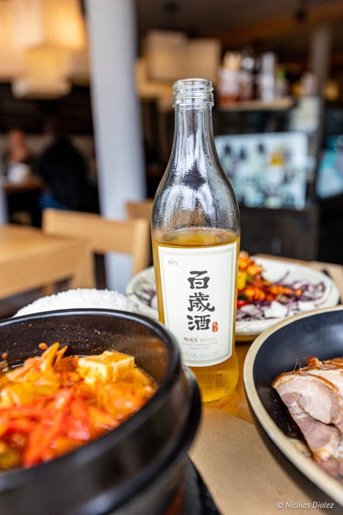 Bouteille de Bekseju et plats coréens au restaurant Bekseju Village Paris.