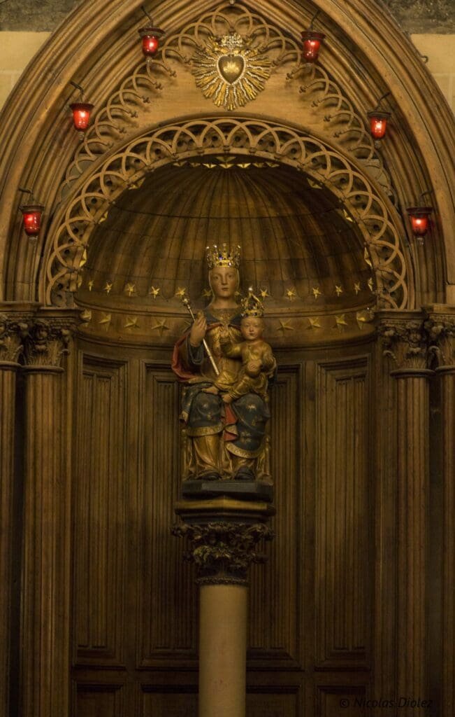 Statue en bois de la Vierge à l'Enfant couronnée dans un encadrement richement sculpté de la cathédrale de Chartres.