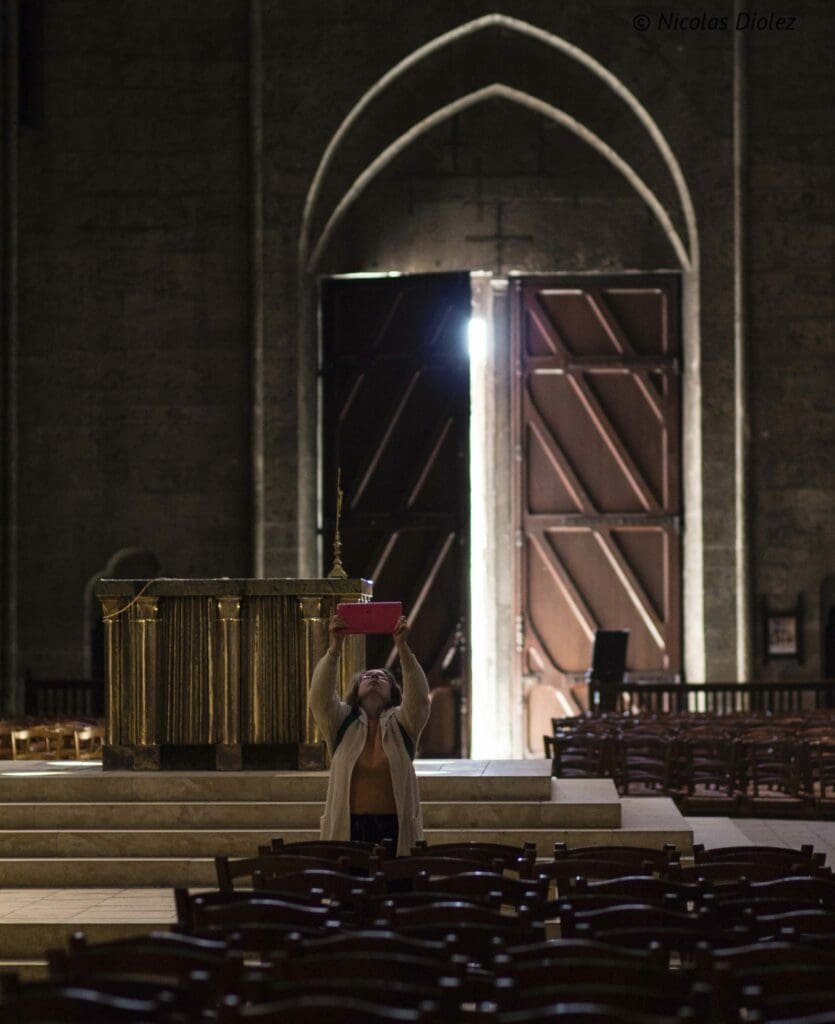 Visiteuse prenant une photo dans l'intérieur sombre de la cathédrale de Chartres.