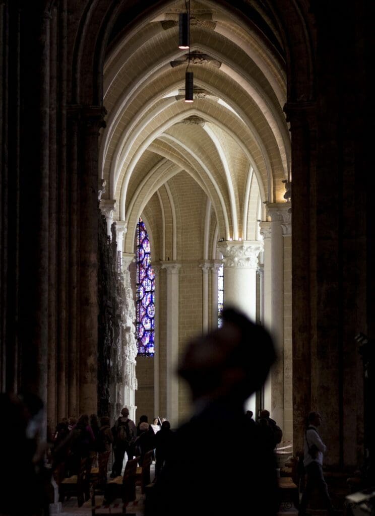 Intérieur de la cathédrale de Chartres, voûtes gothiques et vitrail bleu illuminé.