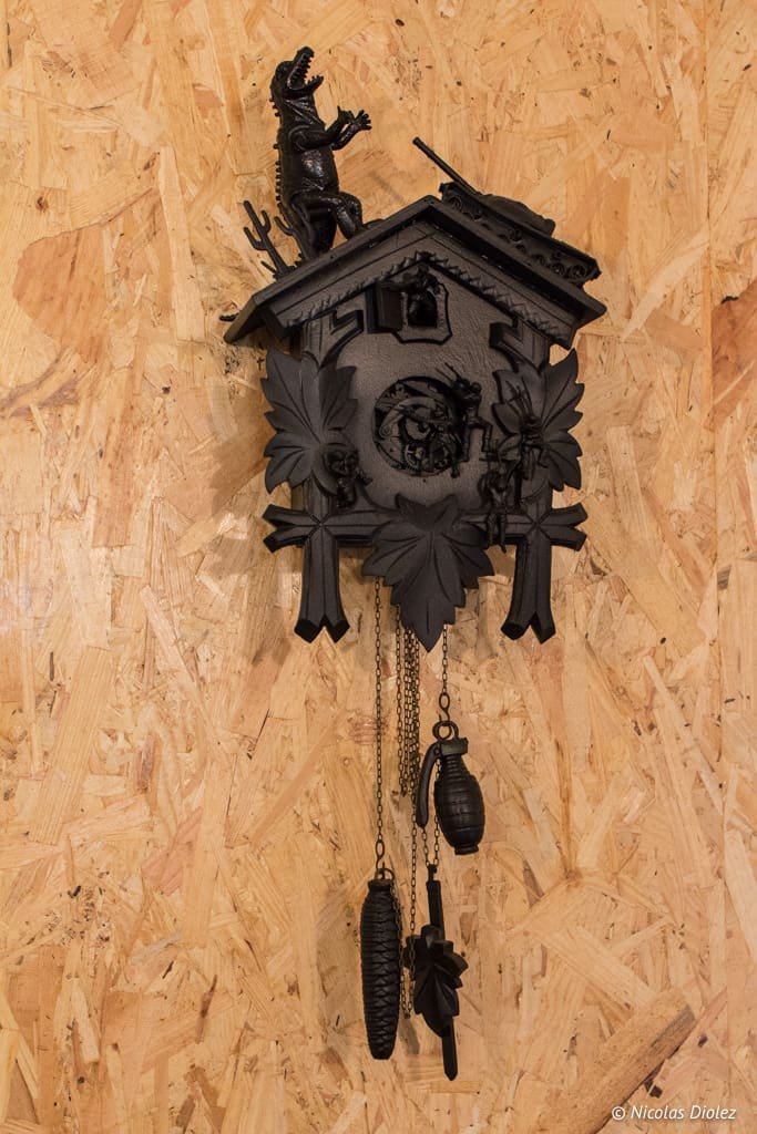 Horloge coucou noire décorée d'un dinosaure, d'un tank et de grenades.