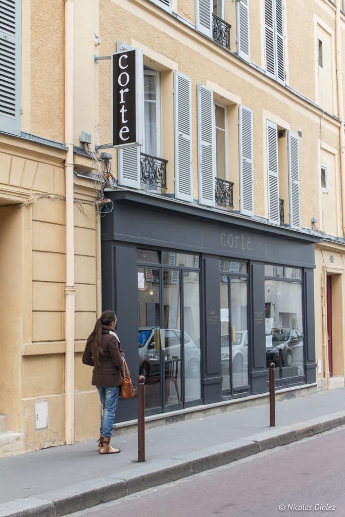 Façade du restaurant Corte à Versailles avec une femme debout sur le trottoir.