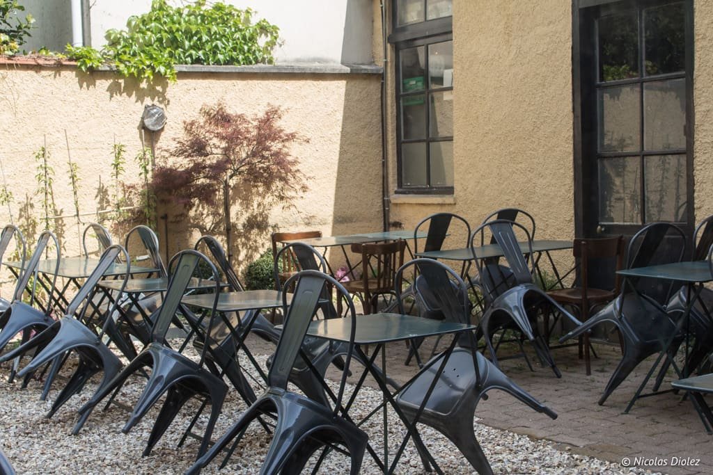 Terrasse de restaurant à Versailles avec chaises métalliques empilées et tables.