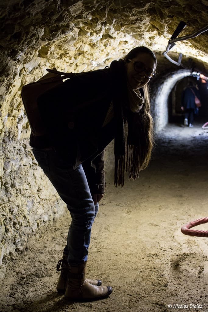 Visite souterraine à Versailles: femme dans un tunnel éclairé.