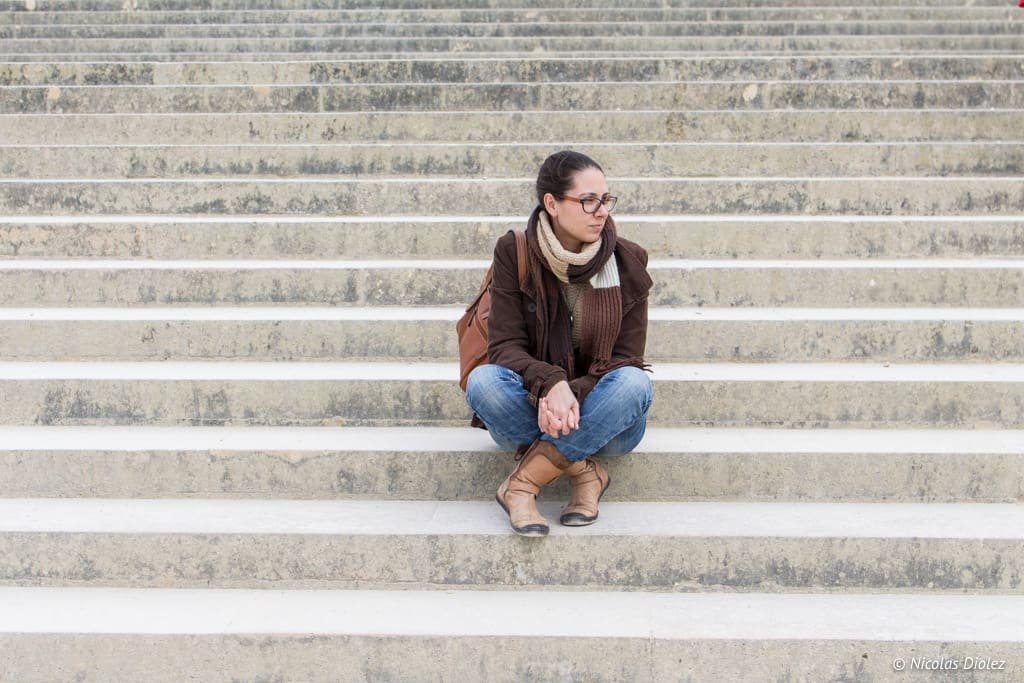 Femme assise sur les marches en pierre du Château de Versailles.