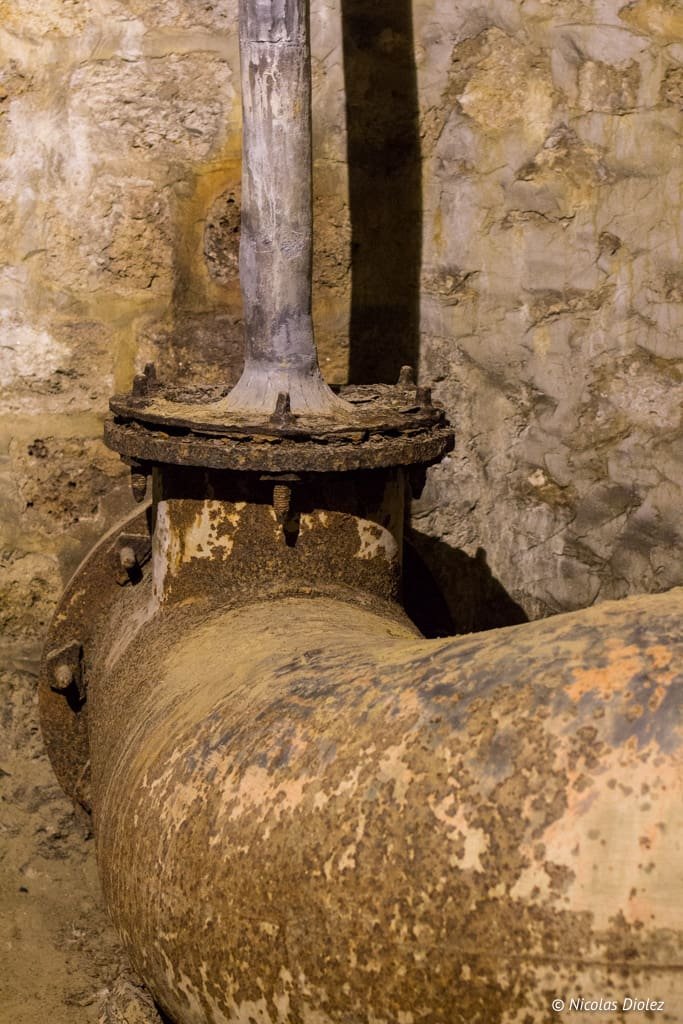 Ancien tuyau rouillé et raccord avec mur de pierre, souterrain des eaux Versailles.