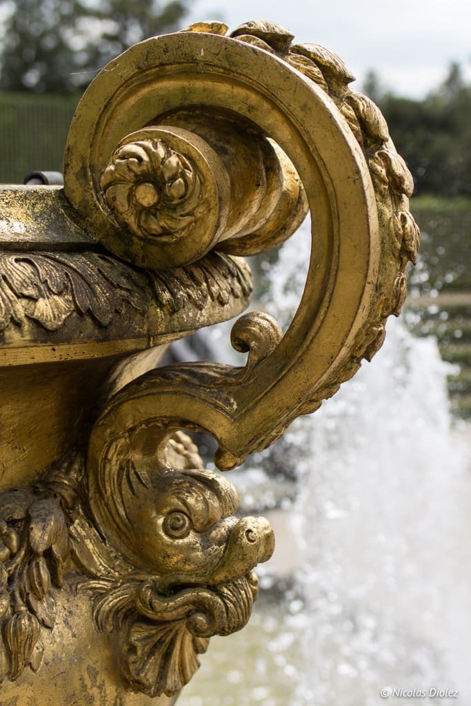 Ornement doré d'une vasque de fontaine dans les jardins de Versailles.