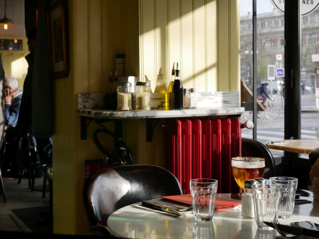 Verre de bière et couverts sur table au Café d'Italie, ambiance lumineuse.