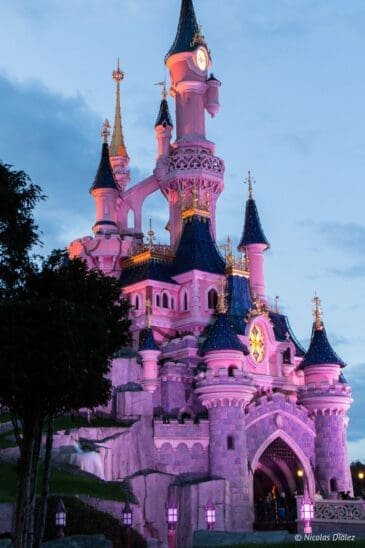 Dornröschenschloss in Disneyland Paris, beleuchtet in der Abenddämmerung.