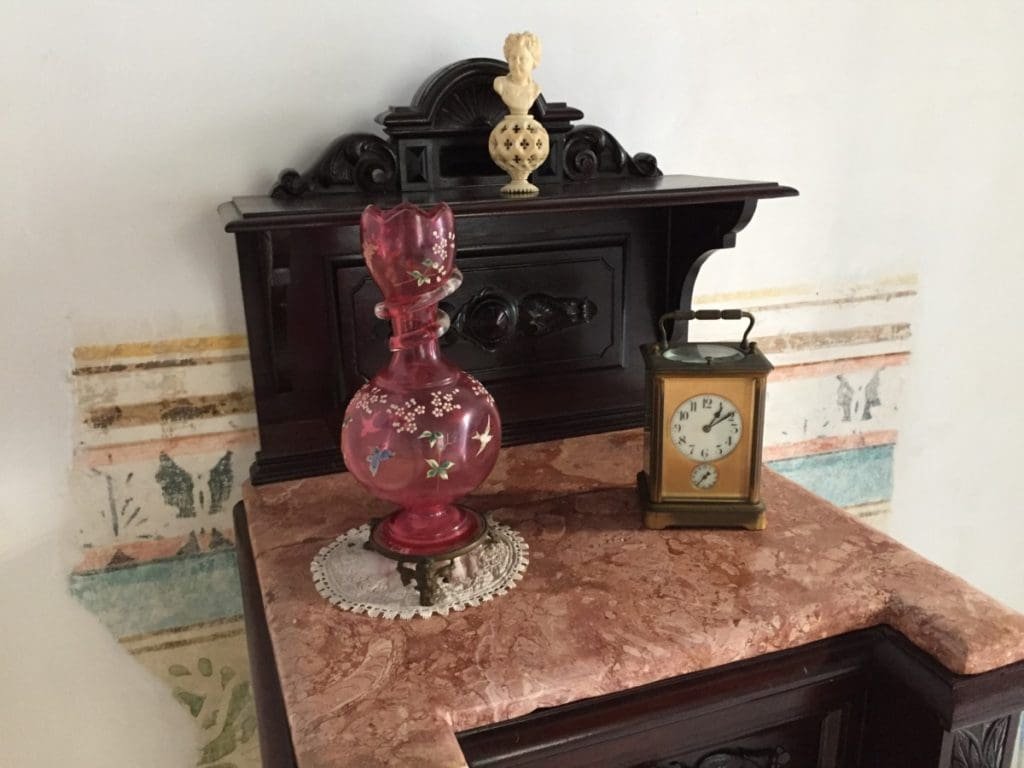 Casa Marques de Arcos. DR Valérie Collet 2018 Vase rose, pendule et buste sur commode en bois foncé à La Maison du Marquis de Arcos.