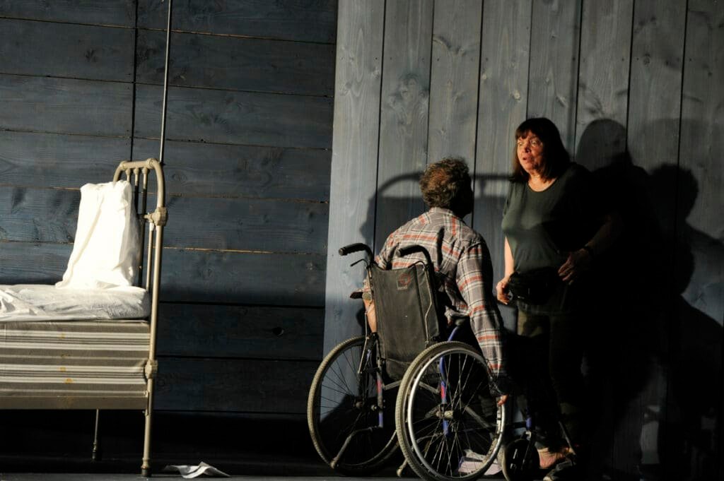 Scene from the play "Misery" with a man in a wheelchair and a woman.