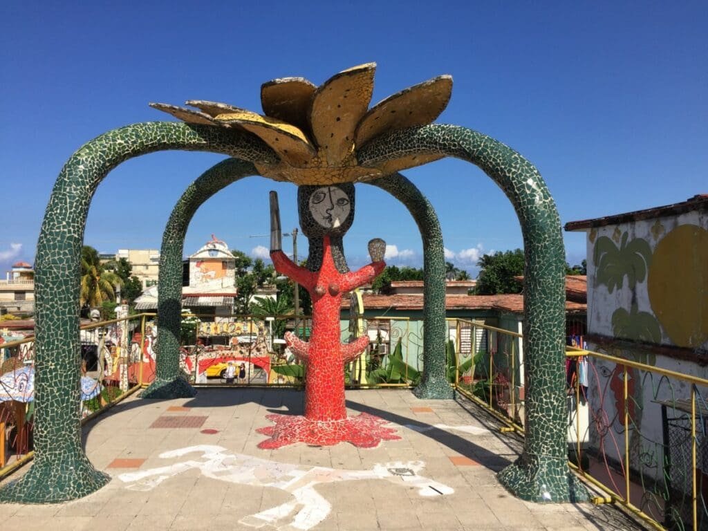 Fusterlandia-DR Valérie Collet 2019 Sculpture mosaïque de Fusterlandia, personnage rouge sous arche fleur jaune.