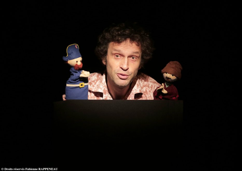 Petit Manuel D'engagement Politique Poppenspeler met twee marionetten op een zwart podium.